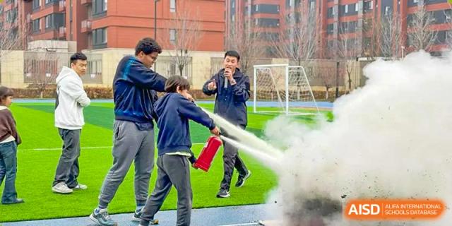 A student at HuZ Deutsche Schule Shenyang practicing with a fire extinguisher under supervision.