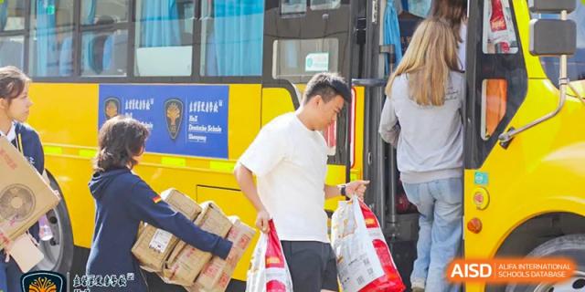 A father and son from HuZ Deutsche Schule Shenyang boarding a yellow school bus with bags.