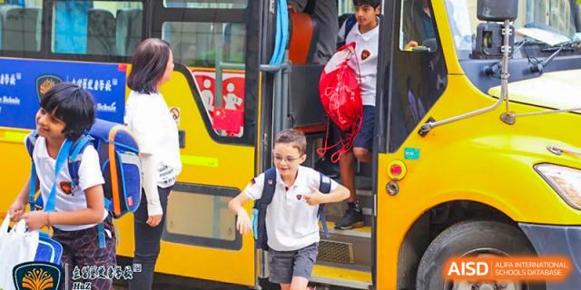 A young student from HuZ Deutsche Schule Shenyang excitedly getting off a school bus.