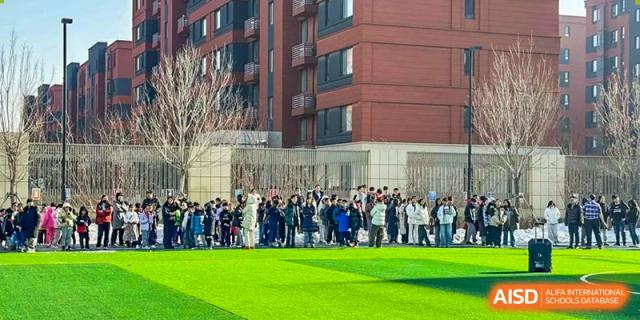 Students and faculty from HuZ Deutsche Schule Shenyang gathered outdoors on a sports field.