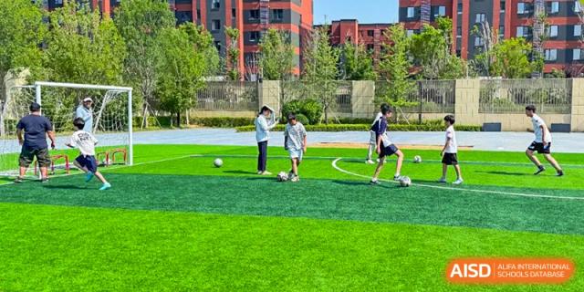 Students from HuZ Deutsche Schule Shenyang playing soccer on a green field.