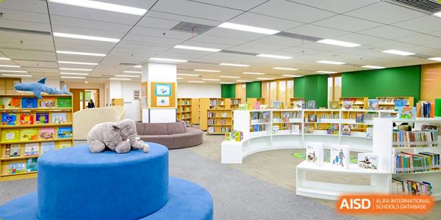 A brightly lit and modern library at Overseas Chinese Academy of Chiway Suzhou with comfortable seating and bookshelves.