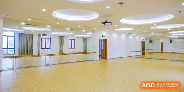 A ballet or dance studio at Overseas Chinese Academy of Chiway Suzhou with a wooden floor and a ballet barre along the mirror.