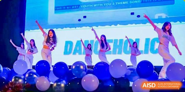 A female student from Overseas Chinese Academy of Chiway Suzhou performing a dance on stage with large blue balloons.
