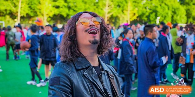 A man with sunglasses from Overseas Chinese Academy of Chiway Suzhou smiling at an outdoor event.