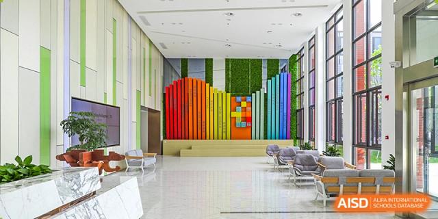 A colorful, modern interior wall at Overseas Chinese Academy of Chiway Suzhou, with a design featuring vertical multicolored stripes and a green wall.