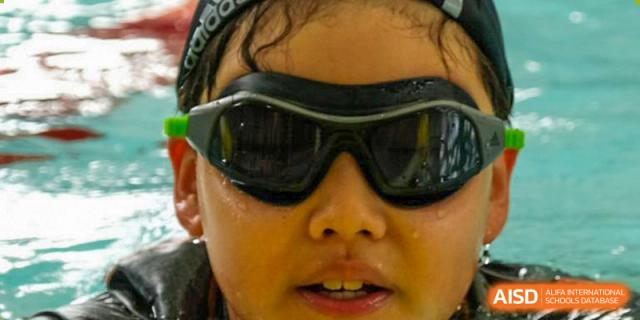 A close-up portrait of a student from Overseas Chinese Academy of Chiway Suzhou wearing swimming goggles.