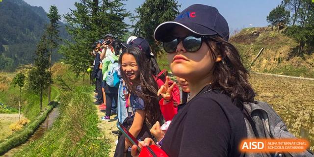 A group of students from Overseas Chinese Academy of Chiway Suzhou smiling and posing for a photo outdoors during a school trip.