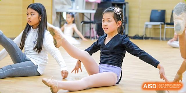 A young female student from Overseas Chinese Academy of Chiway Suzhou practicing ballet in a studio.