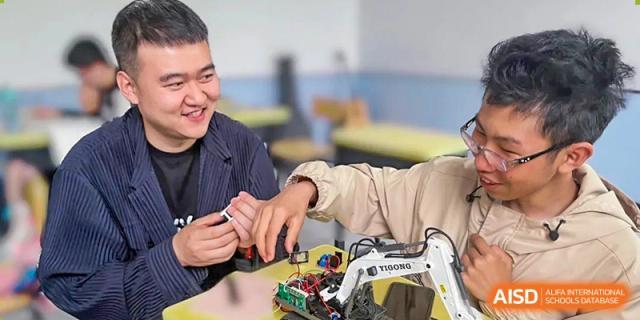 Two students happily work together on a small electronic circuit board and robotics kit at Shanxi Plinth International School.