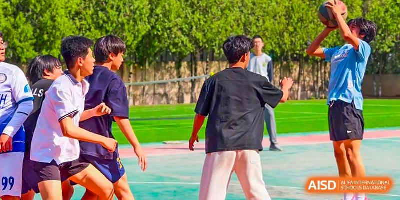 Students playing a sport or engaging in an activity on an outdoor turf or green court area at Shanxi Plinth International School.