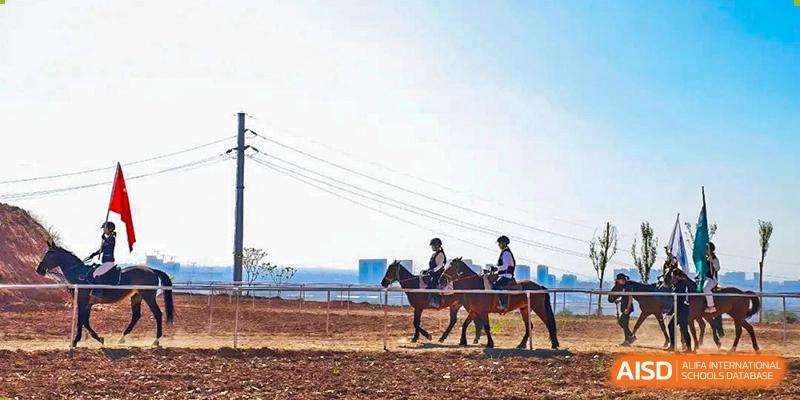Students learning to ride horses in a large open area on the school grounds at Shanxi Plinth International School.
