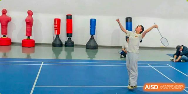Student practicing striking or martial arts indoors near punching bags at Shanxi Plinth International School.