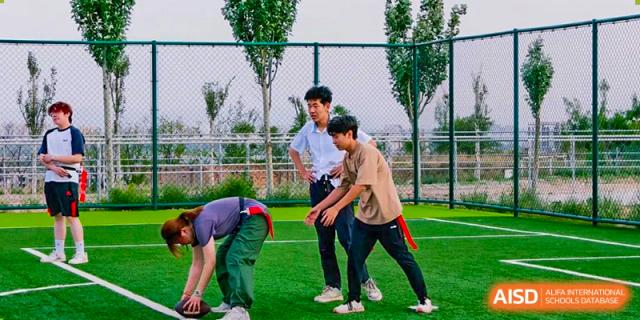 Students playing a field sport, possibly flag football or a similar game, on an outdoor turf court at Shanxi Plinth International School.