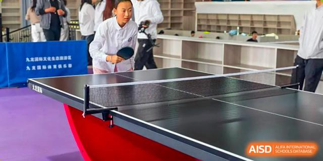Students playing table tennis (ping pong) indoors at a sports facility within Shanxi Plinth International School.