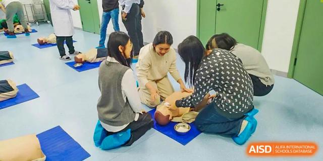 Students practice CPR on a medical dummy during a First Aid class at Shanxi Plinth International School.