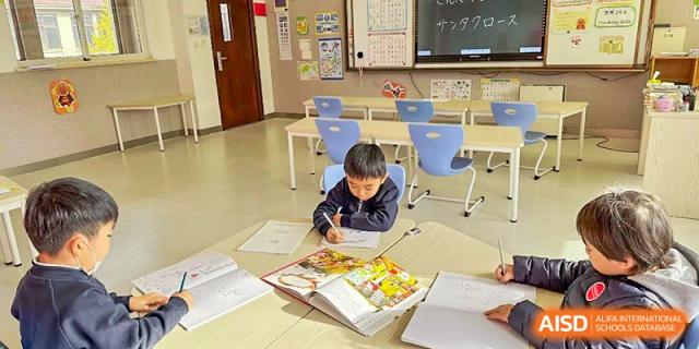 Young student studying or drawing at a small table in a bright classroom at Wuxi Boston International School.