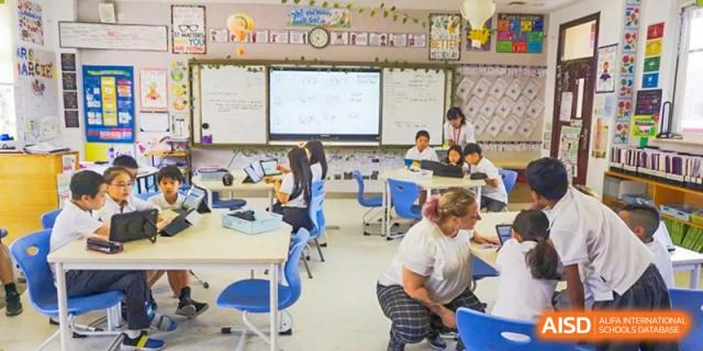 Students in a modern classroom working with an interactive whiteboard at Wuxi Boston International School.