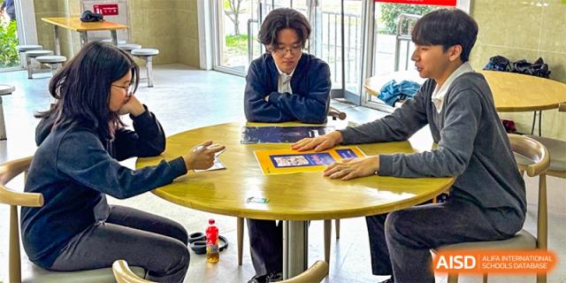 Students engaged in a small-group discussion or activity around a table at Wuxi Boston International School.