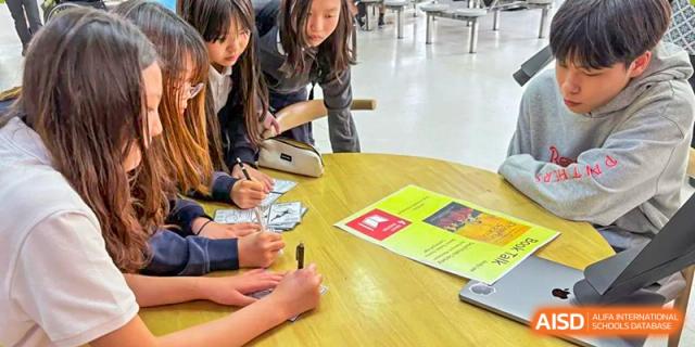 Students and a teacher collaborating on a project around a table at Wuxi Boston International School.