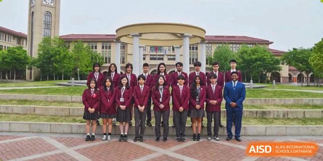 Group of students in uniform posing in front of the school building at Wuxi Boston International School.