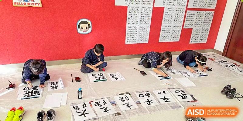 Students practicing calligraphy on large paper on the floor at Wuxi Boston International School.