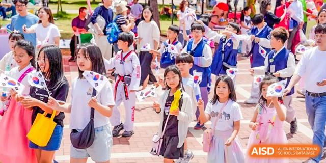 Children in Taekwondo and traditional dress at an outdoor event for Wuxi Boston International School.
