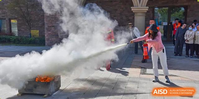 A person demonstrating how to use a fire extinguisher outdoors at Wuxi Boston International School.