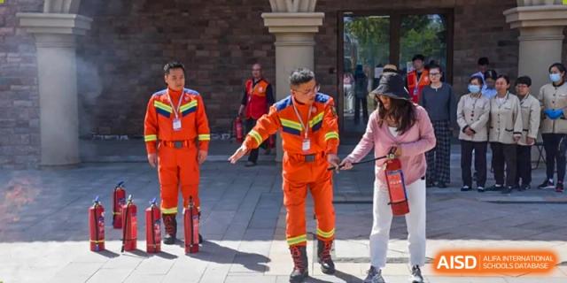 A firefighter in orange gear instructing a group on safety at Wuxi Boston International School.