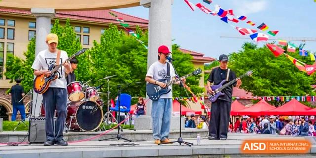 A student playing electric guitar in a band performance at Wuxi Boston International School.