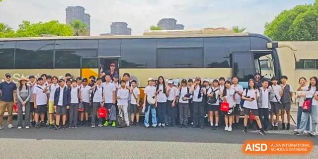 A large group of students and teachers posing for a photo outdoors at Wuxi Boston International School.