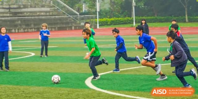 Students running and playing outdoors on the sports field at Wuxi Boston International School.