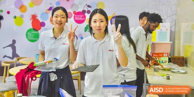 Female student giving a peace sign while speaking or presenting at Wuxi Boston International School.