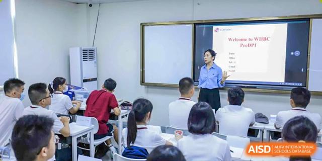 A female teacher addresses students seated at tables in a classroom at Wuhan Britain-China School.
