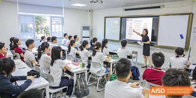 Students sit at individual desks, facing a whiteboard during a lesson in a classroom at Wuhan Britain-China School.