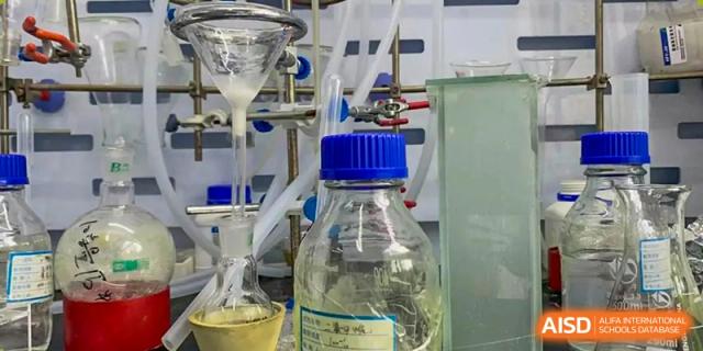 Laboratory glassware, including a bottle with a blue cap and a funnel setup, used for a science experiment at Wuhan Britain-China School.