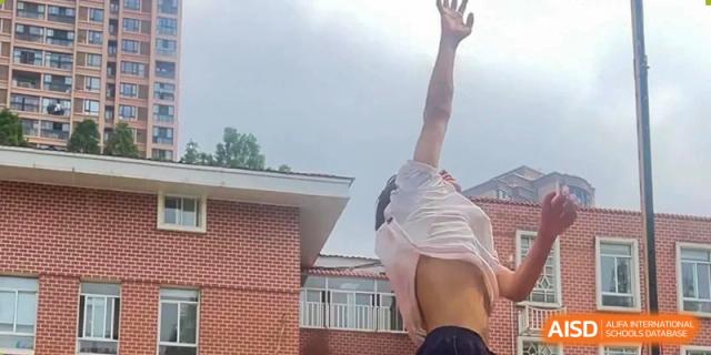 A student from Wuhan Britain-China School outdoors, raising their arms and possibly celebrating or exercising after getting wet.