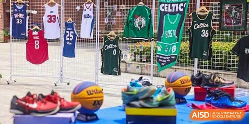 A display of sports merchandise, including a green basketball jersey and athletic shoes, for teams at Wuhan Britain-China School.
