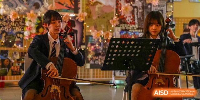 A student from Wuhan Britain-China School playing the cello or violin during a performance or practice session.