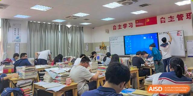 Students sitting at desks working quietly on their studies in a brightly lit self-study classroom, at Ningxiang Country Garden School.