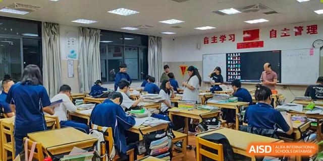 A group of students sitting at clustered desks, actively engaged in a hands-on learning activity or project construction, at Ningxiang Country Garden School.