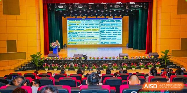 An audience of students seated in an auditorium watching a large stage screen displaying extensive text or data during a school assembly or lecture, at Ningxiang Country Garden School.