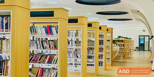 A view of tall, brightly lit wooden bookshelves filled with books, showcasing the school library's resources, at Ningxiang Country Garden School.