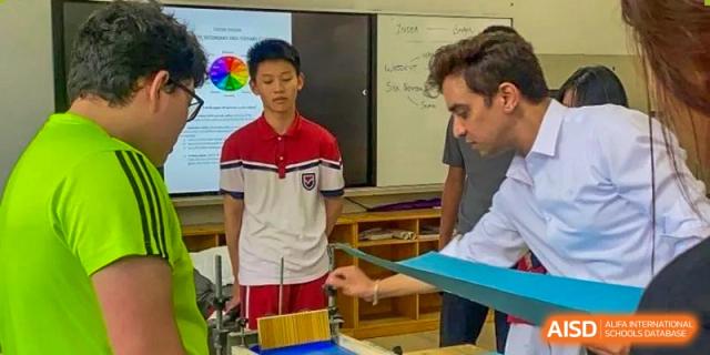 A student in a school uniform interacting with a teacher or instructor next to a whiteboard, engaged in a discussion or demonstration, at Ningxiang Country Garden School.
