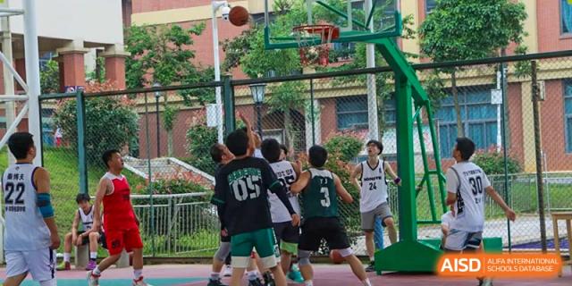 Students actively playing basketball outdoors on a court, competing for the ball under the hoop, at Ningxiang Country Garden School.