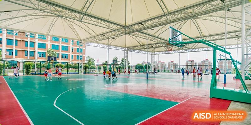 An expansive outdoor multi-purpose sports court with a red and green surface and a large white canopy/shelter overhead, at Ningxiang Country Garden School.