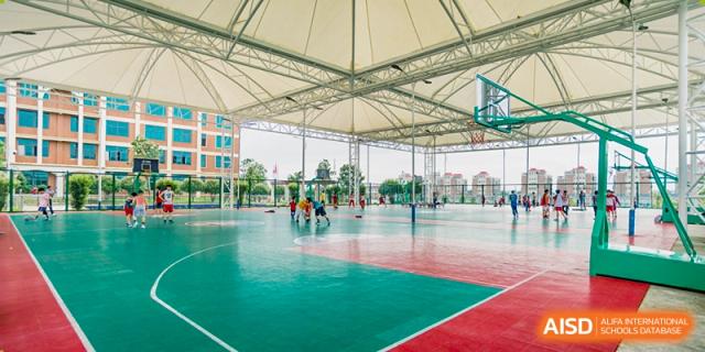 An expansive outdoor multi-purpose sports court with a red and green surface and a large white canopy/shelter overhead, at Ningxiang Country Garden School.