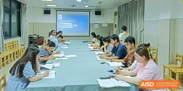 Students seated around a long table in a classroom, attentively taking notes or participating in a group discussion or meeting, at Ningxiang Country Garden School.