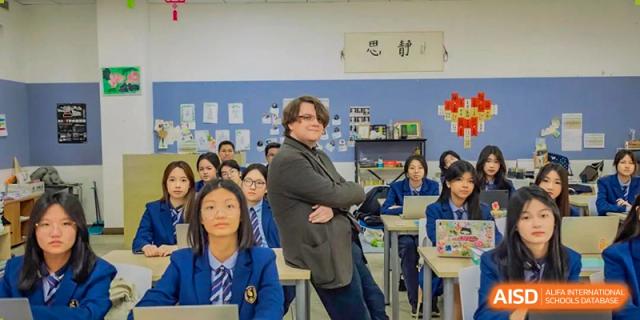 A male teacher strikes a playful pose in front of a classroom full of high school students at Changsha WES (Bilingual) Academy.