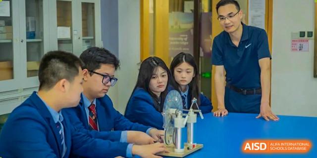 A group of three high school students collaborating on a physics or engineering project involving a small motor and mechanism at Changsha WES (Bilingual) Academy.